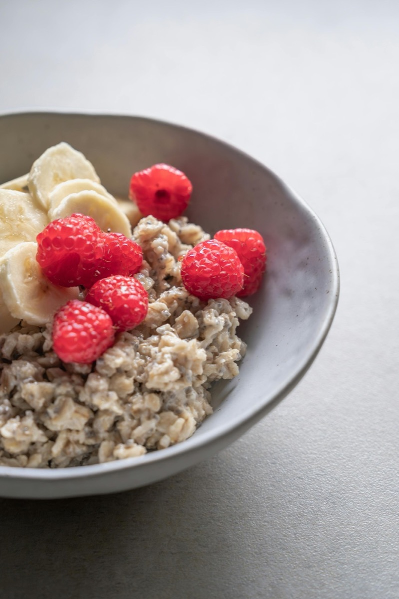 A bowl of oats topped with fruit and seeds
